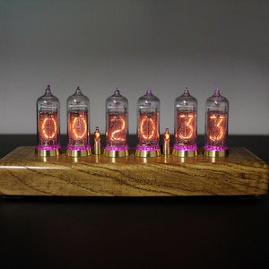 May include: A wooden clock with six clear glass tubes displaying the time as 00:20:33. The tubes have a pink glow and are set on a wooden base.