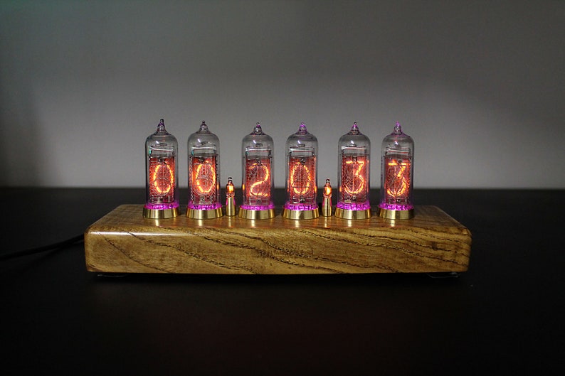 May include: A wooden clock with six clear glass tubes displaying the time as 00:20:33. The tubes have a pink glow and are set on a wooden base.