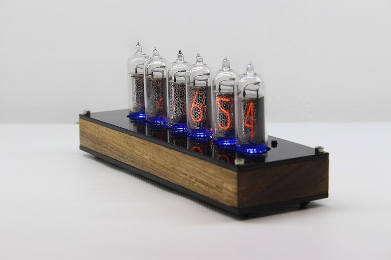May include: A wooden clock with six clear glass Nixie tubes displaying the time as 16:54. The tubes have orange numbers and blue glow around the base.