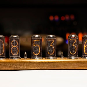 Puede incluir: Una base de madera con seis tubos de vidrio transparentes que muestran los n&uacute;meros 085336 en naranja.