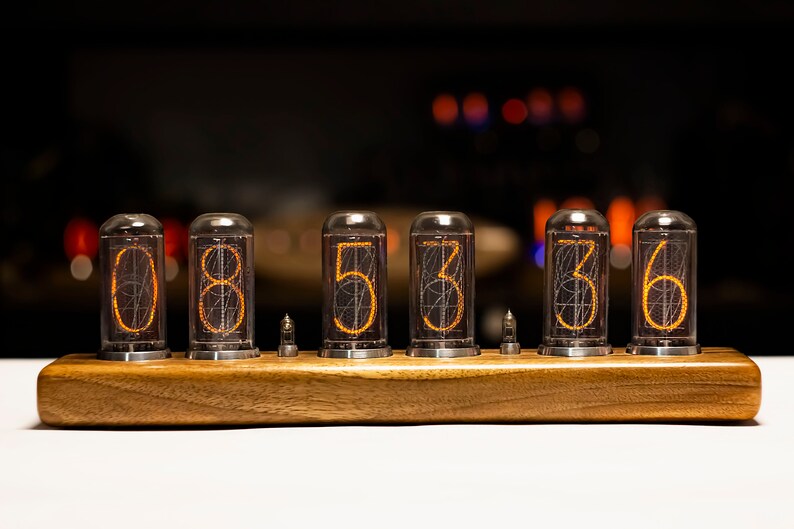 Puede incluir: Una base de madera con seis tubos de vidrio transparentes que muestran los n&uacute;meros 085336 en naranja.