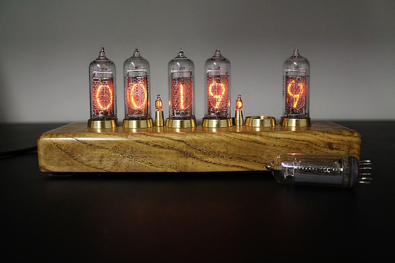 May include: A wooden clock with six glowing Nixie tubes displaying the time "001999". The clock is on a dark surface.