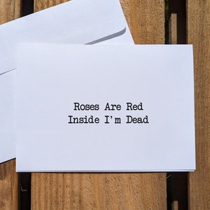May include: A white card with the text "Roses Are Red Inside I'm Dead" written in black font.