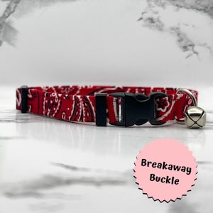 May include: Red and white bandana patterned cat collar with a black breakaway buckle and a silver bell.