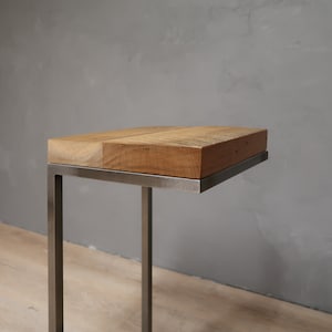 May include: A small wooden table with a metal frame. The table top is made of reclaimed wood and has a natural finish. The metal frame is a simple, rectangular design.