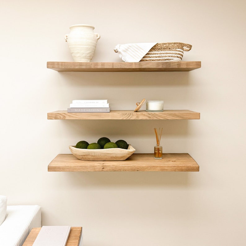 Two Wooden Aged Oak Floating Shelves on a wall with books and decorations