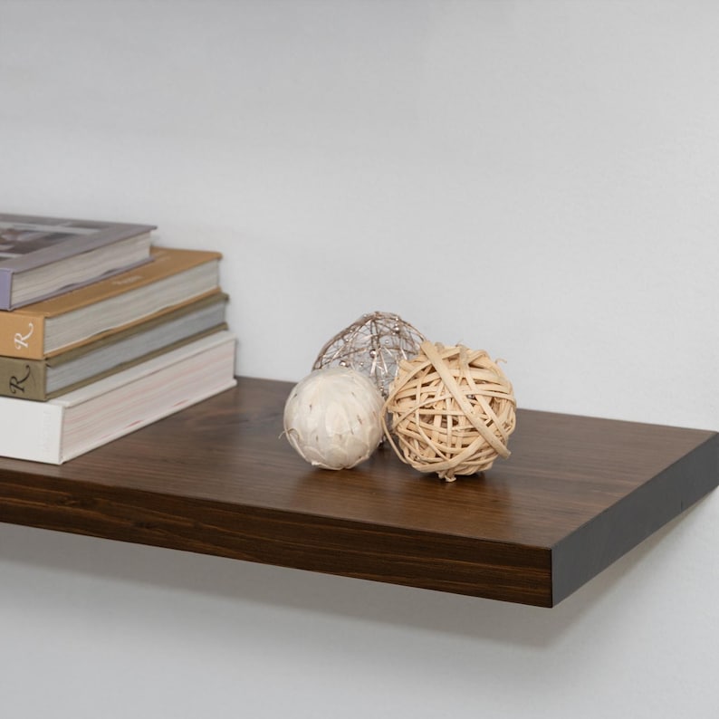 Two Wooden Provincial Floating Shelves on a Wall with Books and Decorations. Heavy duty shelves with floating bracket included.