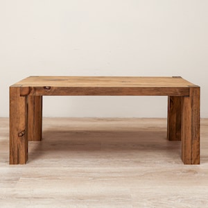 May include: A rectangular wooden coffee table with a natural wood finish and a simple design. The table has four legs and a wide, flat top.