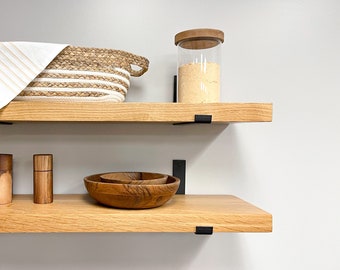 Puede incluir: Dos estantes de madera con soportes de metal negro. El estante superior tiene una cesta tejida y un frasco de vidrio con tapa de madera. El estante inferior tiene dos pequeños frascos de especias y un tazón de madera.