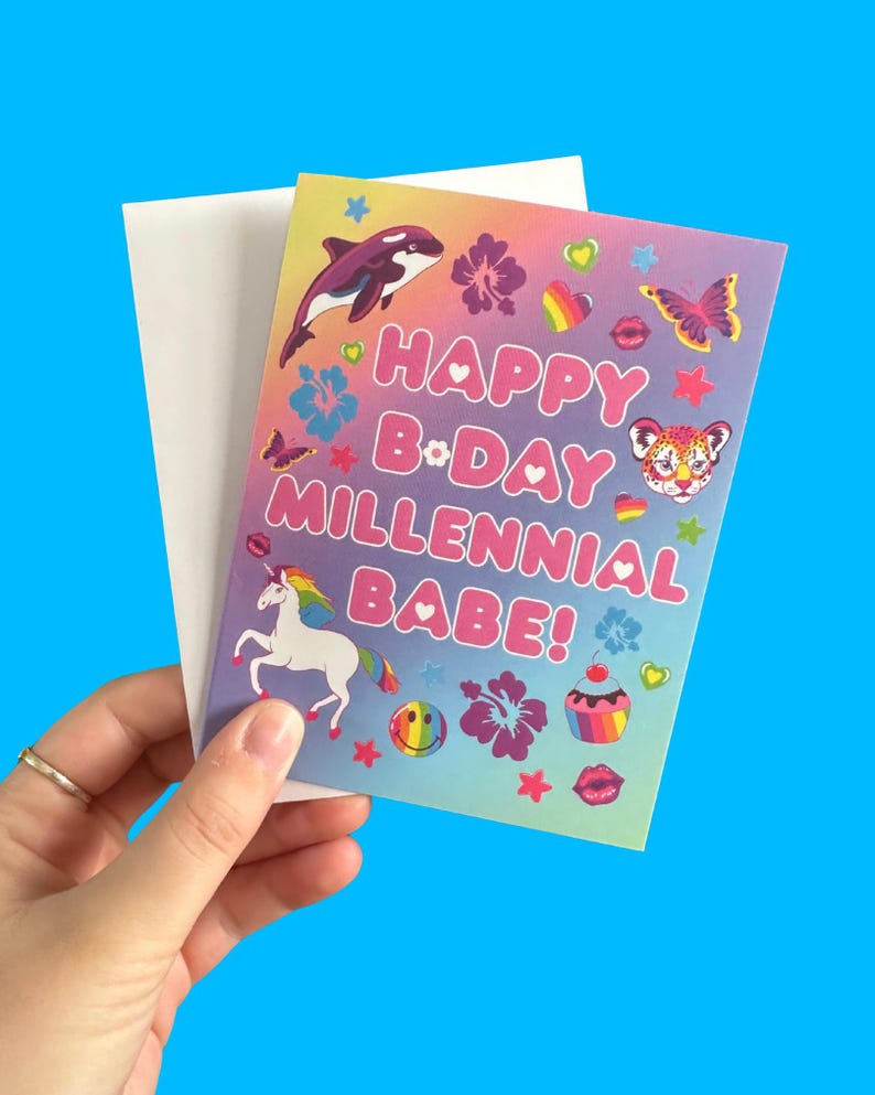 Puede incluir: Una colorida tarjeta de cumplea&ntilde;os con el texto "HAPPY B&bull;DAY MILLENNIAL BABE!" presenta un unicornio arco&iacute;ris, una orca y otros gr&aacute;ficos. La tarjeta se sostiene contra un sobre blanco, con un fondo azul brillante.