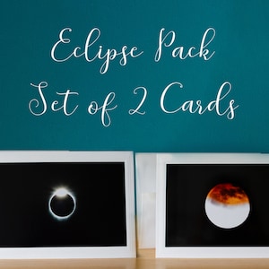 May include: Set of two greeting cards featuring photographs of a solar eclipse and a lunar eclipse. The cards are white with a white envelope.