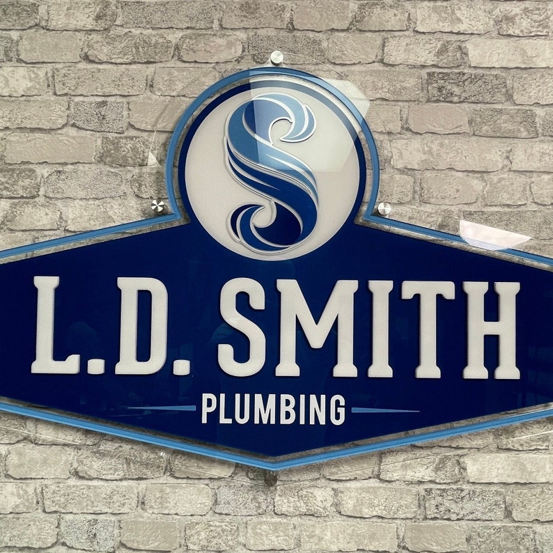 May include: A blue and white sign with the text "L.D. SMITH PLUMBING" and a stylized blue wave design.
