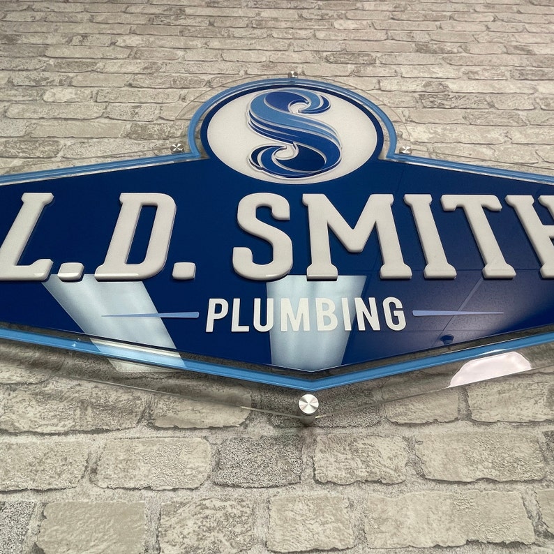 May include: A blue and white sign with the text "L.D. SMITH - PLUMBING" and a stylized blue "S" in a circle.