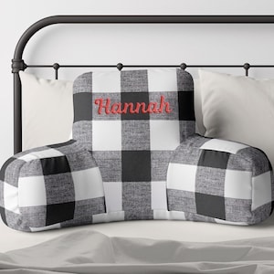 May include: Black and white buffalo plaid reading pillow with the name "Hannah" embroidered in red.