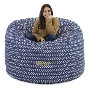 May include: A large, blue bean bag chair with a white chevron pattern. The chair is personalized with the name "MELANIE" in gold lettering.