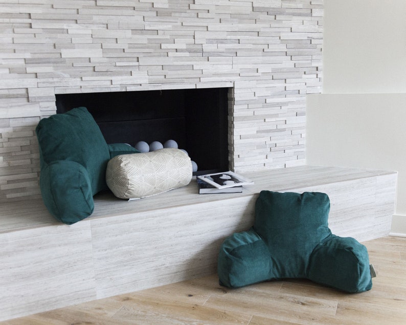 Puede incluir: Una escena de sala de estar acogedora con tres cojines. Dos son cojines de respaldo de color verde azulado, y uno es un coj&iacute;n cil&iacute;ndrico crema con un patr&oacute;n geom&eacute;trico. Los cojines est&aacute;n colocados cerca de una chimenea.