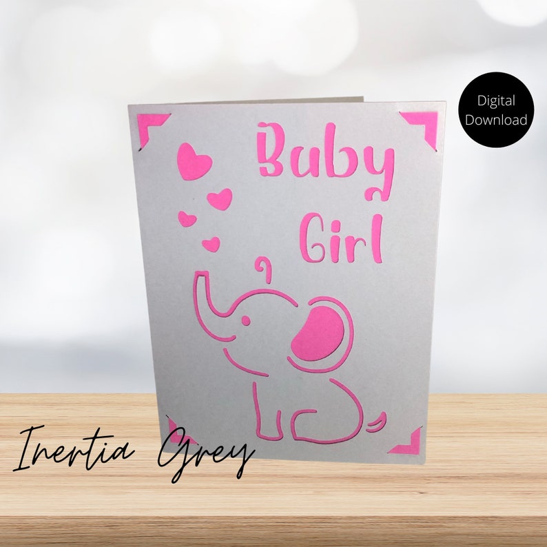 May include: A gray card with a pink elephant and the words "Baby Girl" in pink. There are also several small pink hearts around the elephant.