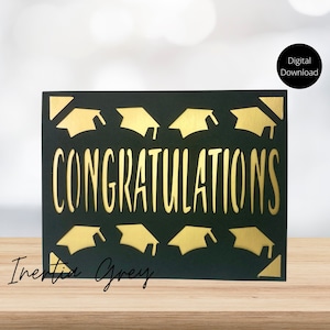 Op de afbeelding: Een zwarte kaart met gouden afstudeerhoeden en het woord "CONGRATULATIONS" in gouden letters. De kaart ligt op een houten oppervlak.