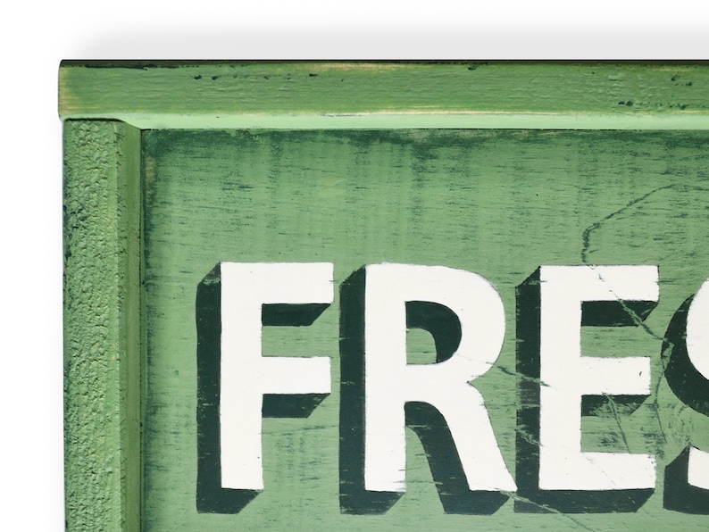 May include: A green wooden sign with white lettering that reads "FRESH". The sign has a distressed look and is perfect for a farmhouse or rustic decor style.