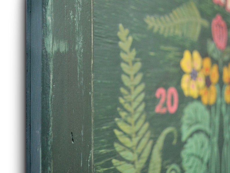 May include: A green wooden sign with a painted floral design. The sign has the number 20 painted in pink on it.