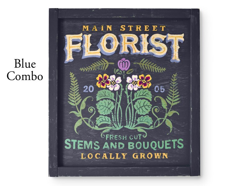 May include: A vintage-style sign with the text "Main Street Florist" in a decorative font. The sign is painted on a dark blue background with a floral design and the text "Fresh Cut Stems and Bouquets Locally Grown".