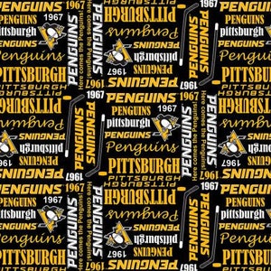 Może przedstawiać: Czarny i złoty materiał z powtarzającym się wzorem logo Pittsburgh Penguins, nazwy drużyny i roku 1967. Tekst "Here comes the Penguins!" powtarza się w całym wzorze.