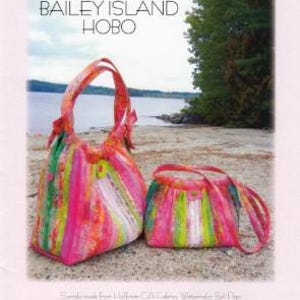 May include: Two colorful fabric bags, a large hobo bag and a smaller purse, sit on a sandy beach. The bags are made from striped fabric in shades of pink, green, and yellow. The text "BAILEY ISLAND HOBO" is visible.