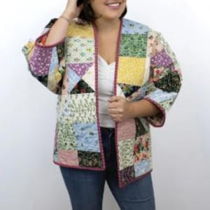 May include: A patchwork quilted clover coat with a variety of colorful fabric squares. The coat has a red trim and is worn over a white top and blue jeans. The text at the bottom reads "clover coat" and "a simple quilted garment | sizes XS to XL."