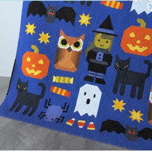 May include: A blue quilt with a Halloween theme. It features a variety of characters and objects, including a witch, an owl, a ghost, bats, pumpkins, candy corn, and black cats. The quilt is made with a variety of fabrics and textures.