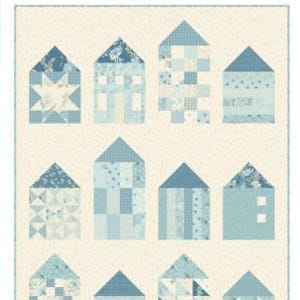 May include: A pieced quilt pattern titled Quilter's Village by Laundry Basket Quilts. The design features twelve house-shaped blocks in various shades of blue and cream, arranged in a grid. The finished quilt size is 32 inches by 41.5 inches.