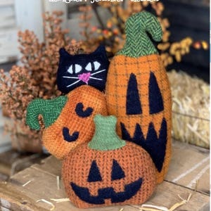 May include: Handmade Halloween decorations featuring a black cat and three orange pumpkins with carved faces. The pumpkins have green stems and are approximately 6.5 inches in height. The text "cottonwood creations" and "Pumpkin Patch" are visible.