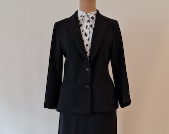 May include: A black blazer and skirt suit on a mannequin. The blazer has a single button closure and the skirt is knee-length.