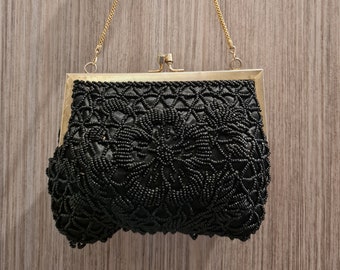 May include: A black beaded evening bag with a gold chain strap. The bag has a floral design and a clasp closure.