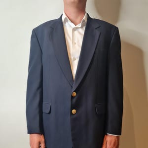 May include: A navy blue blazer with gold buttons. The blazer has a single breasted closure and two flap pockets.
