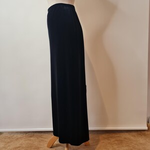 May include: A black maxi skirt made of a soft, stretchy fabric. The skirt is fitted at the waist and flows out to the hem.
