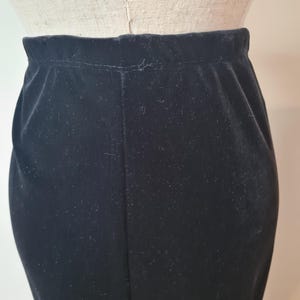May include: A black velvet skirt with a straight silhouette. The skirt is made of a soft, smooth fabric and has a simple design.