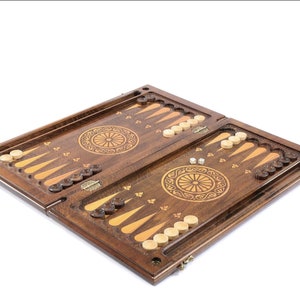 May include: A wooden backgammon set with intricate carvings and a traditional design. The board is open, revealing the playing surface and the pieces.