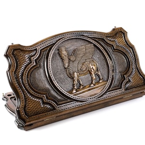 Puede incluir: Una caja de juego de madera con tallas intrincadas. La tapa presenta una talla en relieve detallada de un toro alado, s&iacute;mbolo de la antigua Mesopotamia.