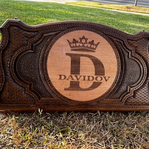 May include: A dark brown wooden box with a carved design. The box has a circular inlay with a light wood background and a dark wood letter "D" surrounded by a crown and the text "DAVIDOV".