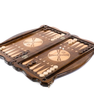 Puede incluir: Un juego de backgammon de madera con un acabado marr&oacute;n. El tablero est&aacute; abierto y las fichas est&aacute;n dispuestas en el tablero. El tablero tiene un dise&ntilde;o decorativo con un c&iacute;rculo en el centro.