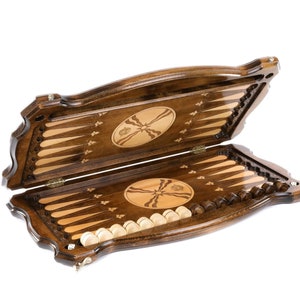 Puede incluir: Un juego de backgammon de madera con un acabado marr&oacute;n y tallas intrincadas. El juego est&aacute; abierto, revelando el tablero de juego y las piezas.