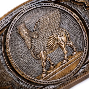 Puede incluir: Un tablero de juego de madera con tallas intrincadas. El centro presenta una talla detallada de un toro alado, s&iacute;mbolo de la antigua Mesopotamia. El tablero est&aacute; decorado con un patr&oacute;n geom&eacute;trico.