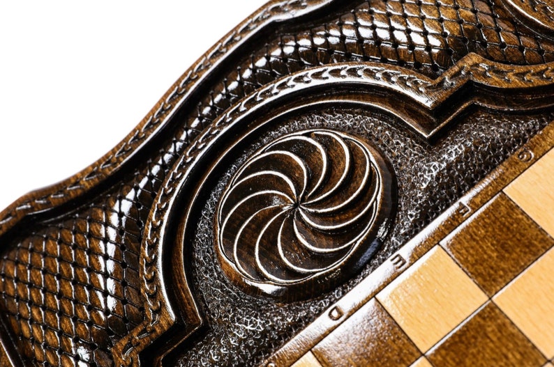 Puede incluir: Primer plano de un tablero de ajedrez de madera con un dise&ntilde;o geom&eacute;trico tallado en el centro. El tablero est&aacute; hecho de madera oscura con una incrustaci&oacute;n de madera clara. El tablero de ajedrez est&aacute; en un marco decorativo con un dise&ntilde;o tallado.