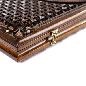 May include: A wooden box with a woven pattern on the lid and a brass latch. The box is closed and the latch is fastened.