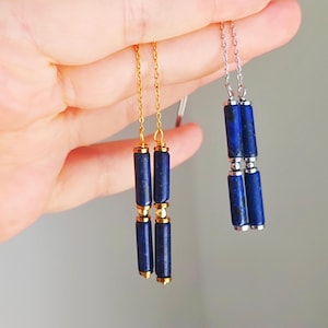 Könnte beinhalten: Zwei Paar Hängeohrringe mit blauen Lapislazuli-Perlen. Ein Paar hat eine goldene Kette und das andere eine silberne Kette.