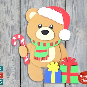 May include: A brown teddy bear wearing a red and white Santa hat, a green and red scarf, and holding a red and white candy cane. The bear is standing next to two wrapped presents, one green and red and the other blue and yellow. The text "Craft with Sarah" is in the lower right corner of the image.