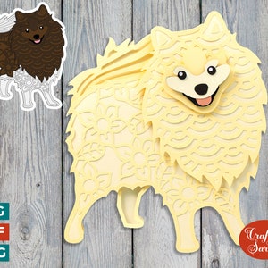 Puede incluir: Una manualidad de papel en capas de un perro Pomerania en tonos amarillos y crema, con intrincados recortes florales. También hay una versión de pegatina más pequeña del perro. La imagen incluye el texto "SVG, DXF, PNG" y "Craft with Sarah".