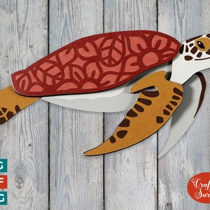 Puede incluir: Una tortuga marina de papel en capas con un caparazón estampado en rojo, blanco y marrón. La tortuga está en vuelo con la cabeza girada hacia la derecha. El fondo es un patrón de veta de madera.