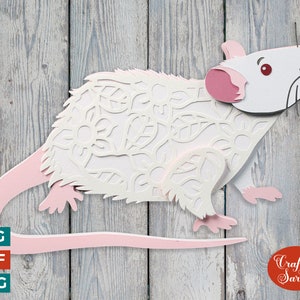 May include: White paper rat with pink ears and tail, cut out with a floral design. The rat is on a wood background with the text "Craft with Sarah" in red.
