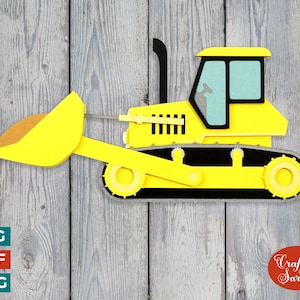 Puede incluir: Bulldozer amarillo con una oruga negra y una pala grande amarilla. El bulldozer está sobre un fondo de madera.